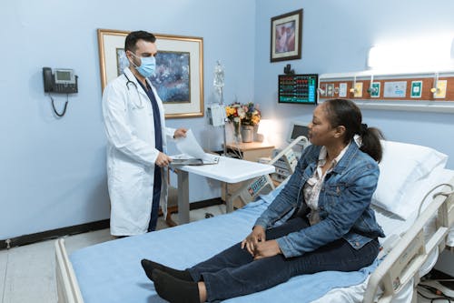 Free Woman in Blue Denim Jacket Sitting on Hospital Bed Stock Photo