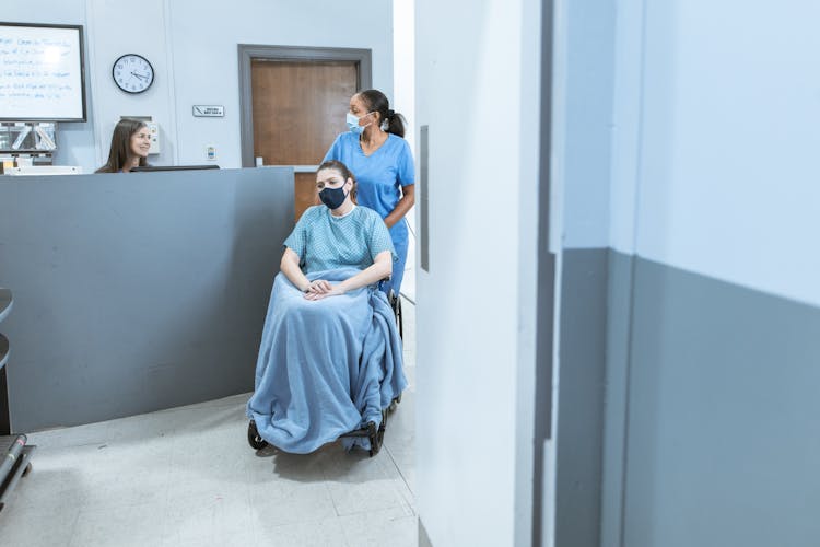 Nurse Assisting A Patient Sitting On A Wheelchair