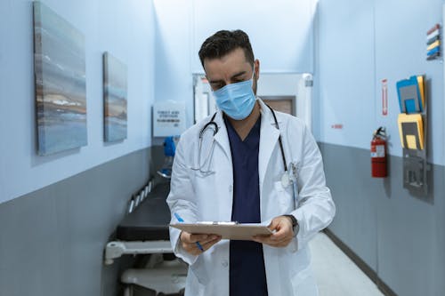 Free Doctor with a Face Mask Reading a Medical Chart Stock Photo