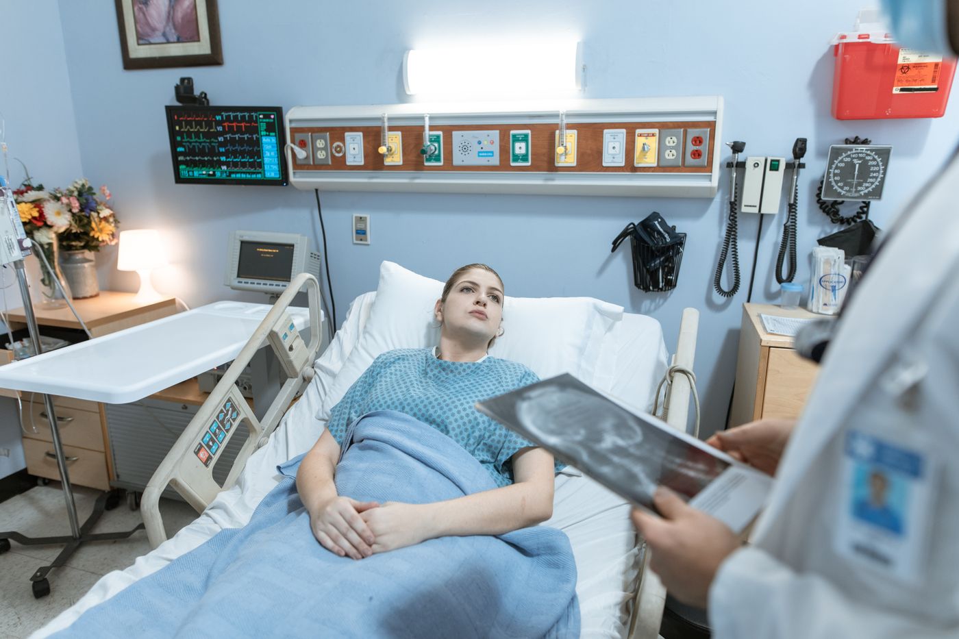Physician checking a seated patient's pulse oximeter reading during an exam-room visit