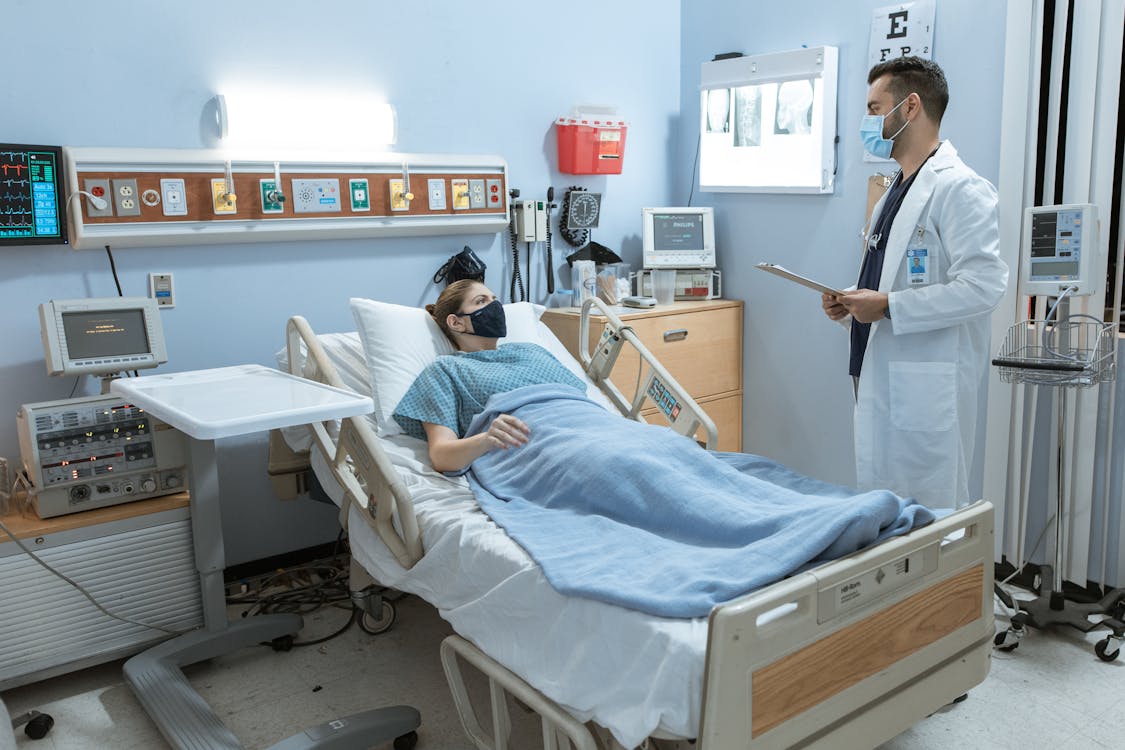 Free Doctor Talking to a Patient Lying Down on a Hospital Bed Stock Photo