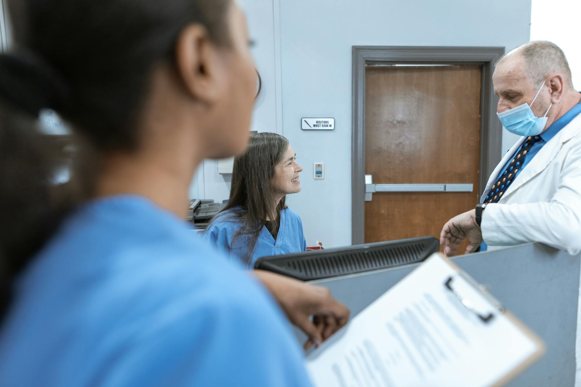 Healthcare professionals in discussion at a hospital reception, emphasizing teamwork and communication.