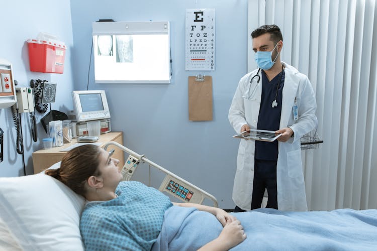 Doctor Talking To A Patient Lying Down On A Hospital Bed