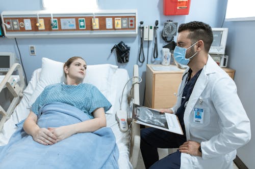 Free Doctor Talking to a Patient Lying Down on a Hospital Bed Stock Photo