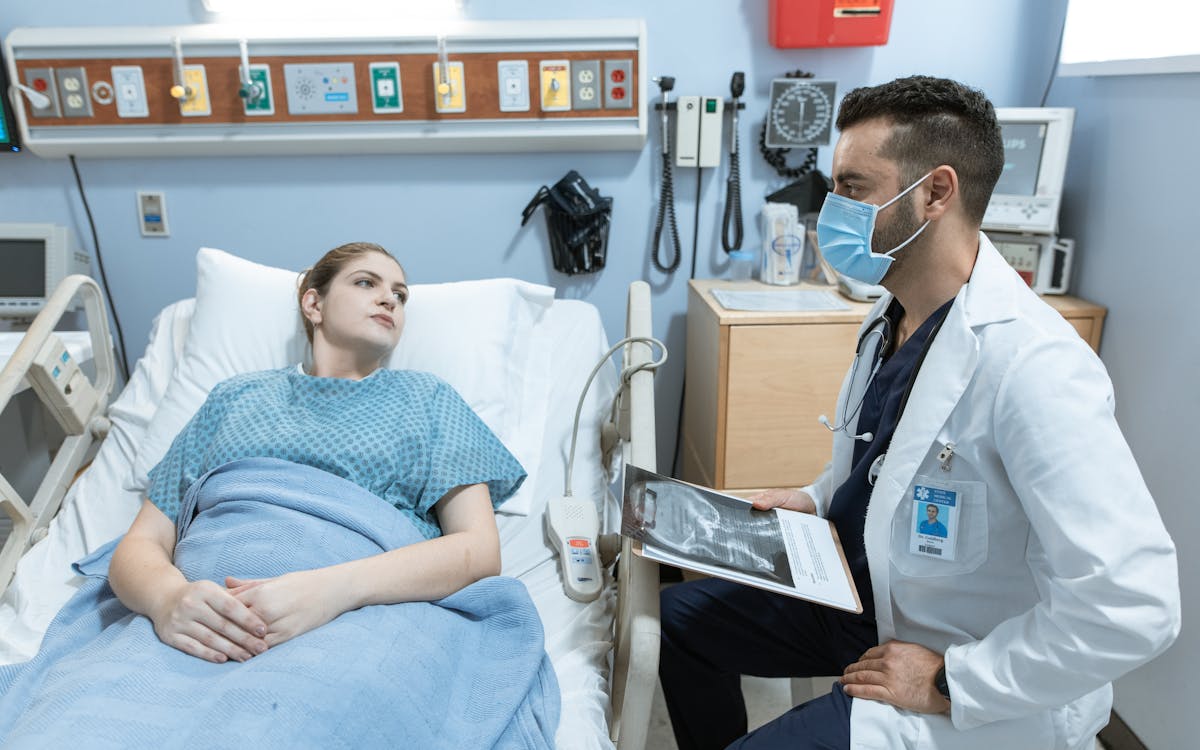 A medical practitioner discusses health details with a patient in a hospital setting.