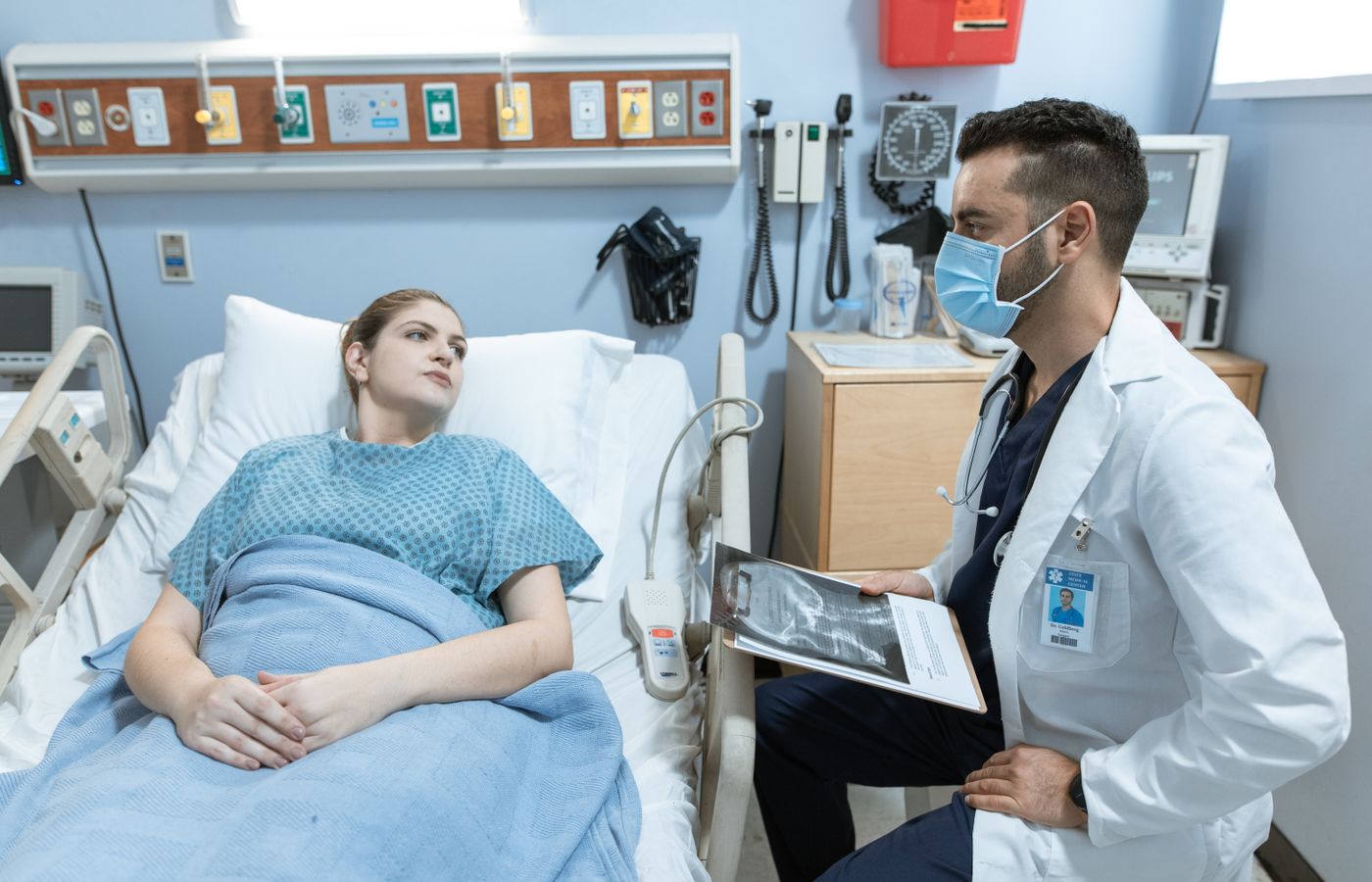 A medical practitioner discusses health details with a patient in a hospital setting.