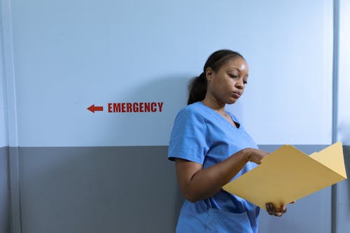 Nurse Leaning on the Wall while Reading a Document