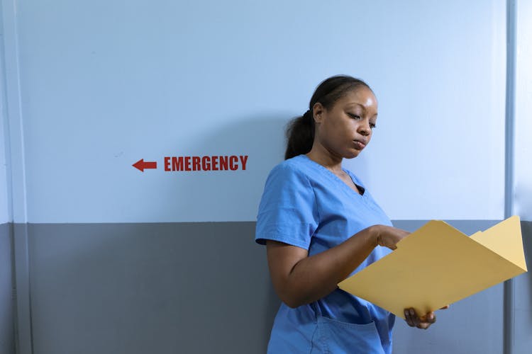 Nurse Leaning On The Wall While Reading A Document