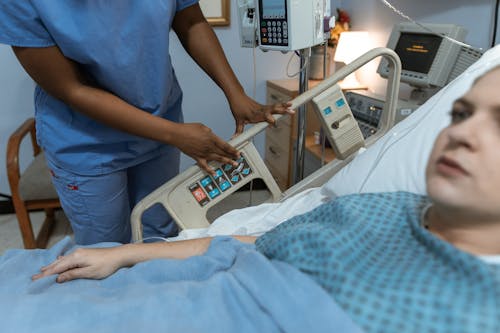 파란색 셔츠와 회색 바지를 입고 병원 침대에 서있는 사람