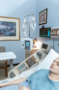 Adult woman lying in hospital bed with medical equipment in a healthcare setting.