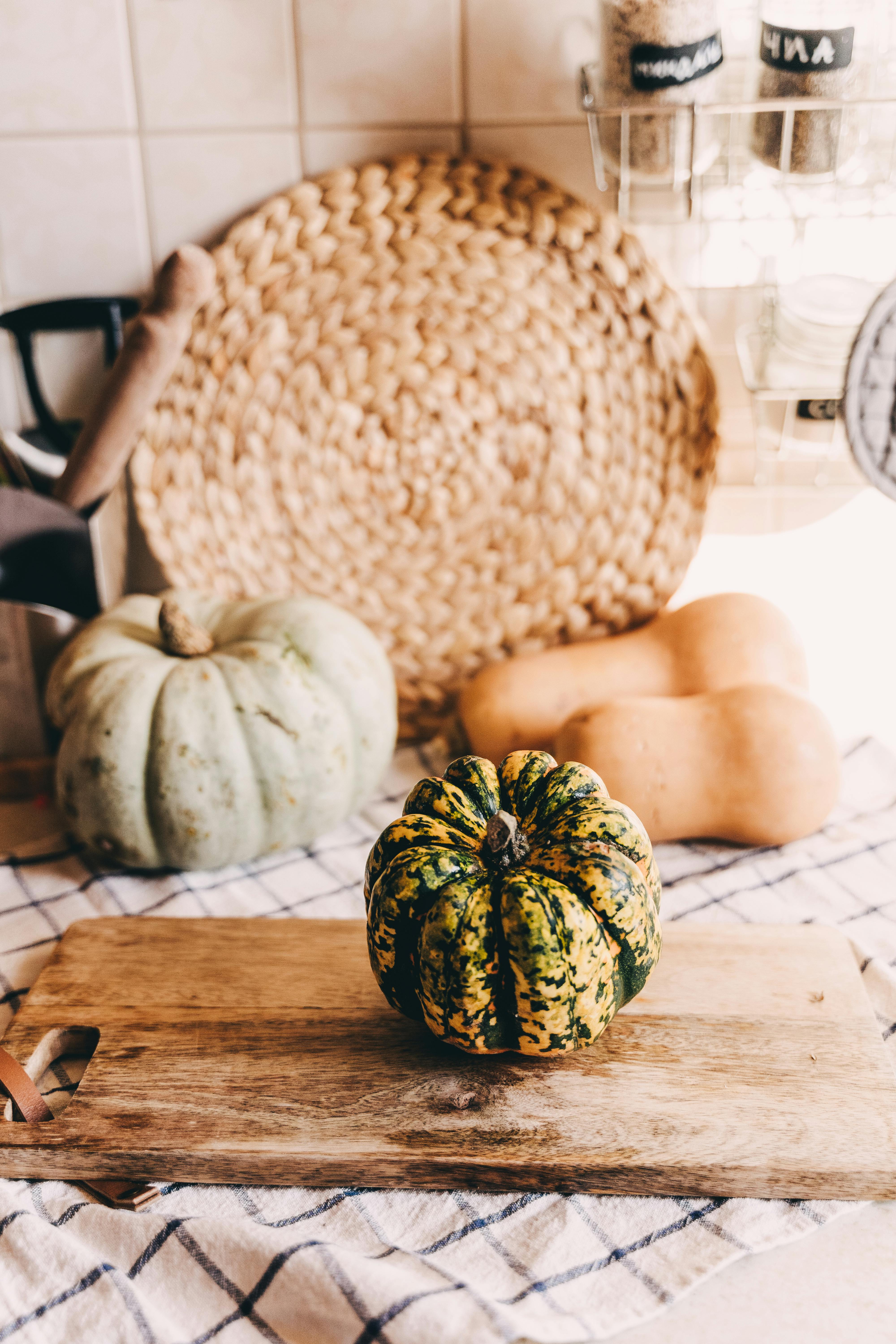 A variety of colorful gourds displayed on a rustic wooden board in a cozy kitchen setting.