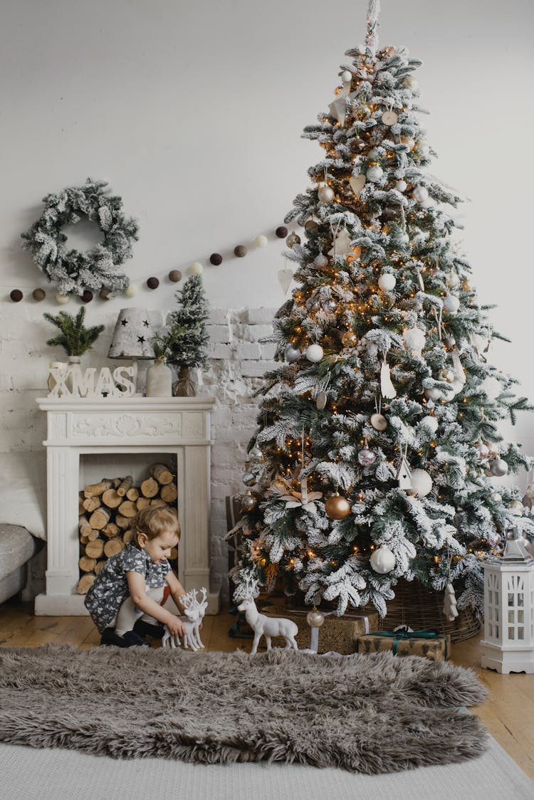 A Child Playing Near A Christmas Tree