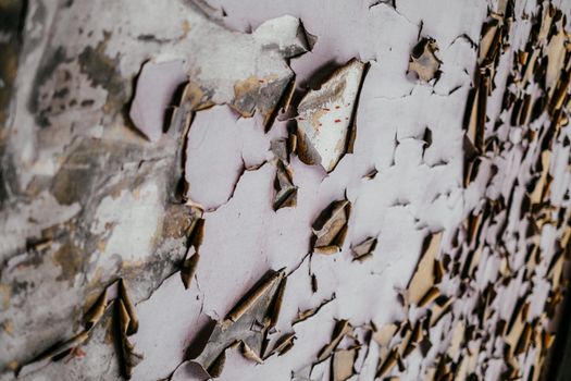 Detailed view of peeling paint on aged, textured wall, showcasing decay and pattern.