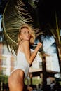 巴厘岛棕榈树下穿着白色泳衣的白人妇女，散发着夏日的气息