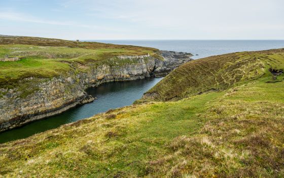 Idyllic view of coastal cliffs and grasslands in Scotland, showcasing natural beauty and tranquility.