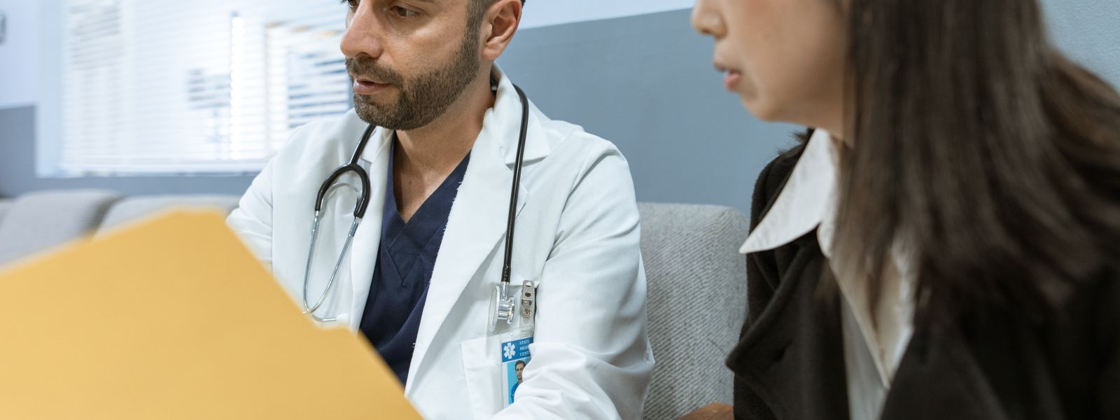 Doctor discusses health records with a patient in a clinical setting.