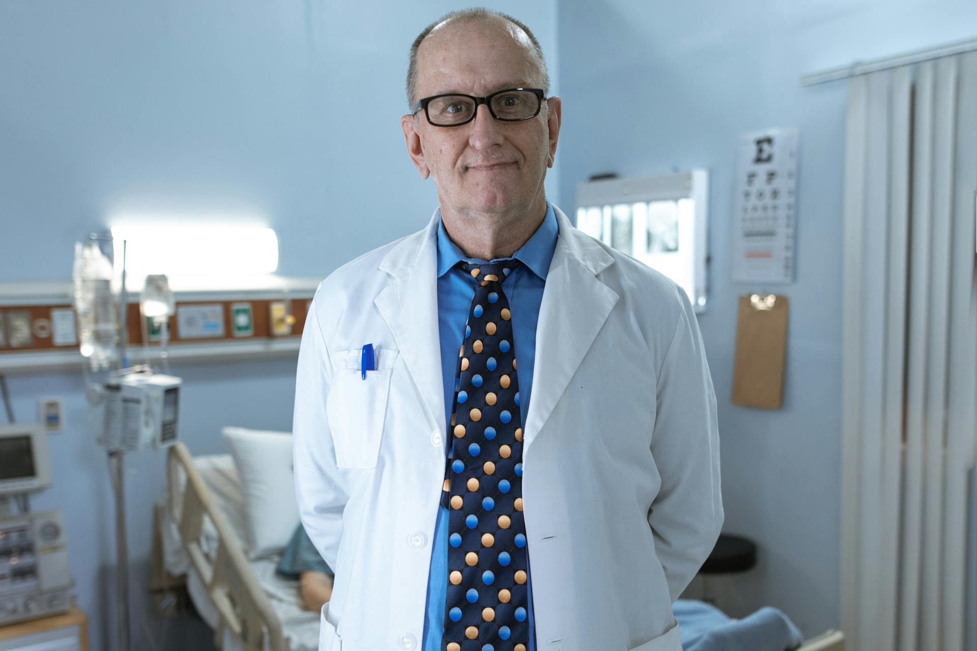 Experienced doctor standing confidently in a hospital room with medical equipment.