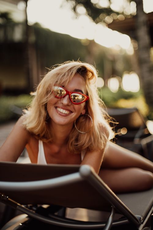 Free Happy woman with blonde hair and sunglasses smiling while relaxing outdoors in Bali, Indonesia. Stock Photo