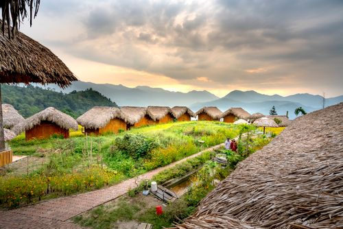 Free Small houses in settlement near mountains and green grass with pavement in daylight under cloudy sky Stock Photo