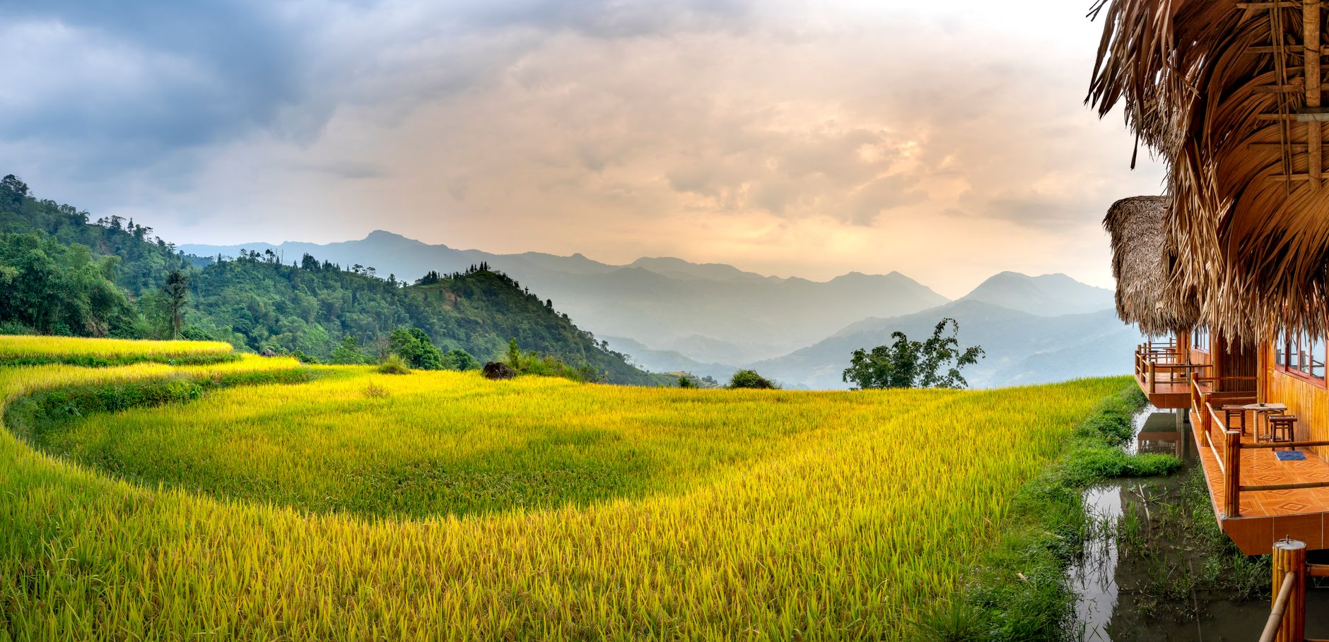 Small houses in settlement near mountains and green grass in daylight under bright sky