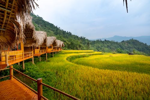 Free Small village with houses near hills and forest on green grass under blue sky in daytime Stock Photo