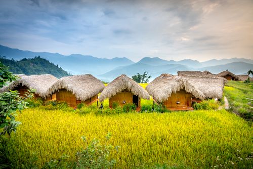 Free Small village with houses on green grass near hills and trees under bright sky in countryside in daytime Stock Photo