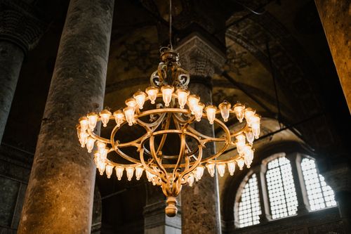 Free Low angle of old lighting up chandelier hanging from dome with pillars in eastern ancient religious cathedral Stock Photo