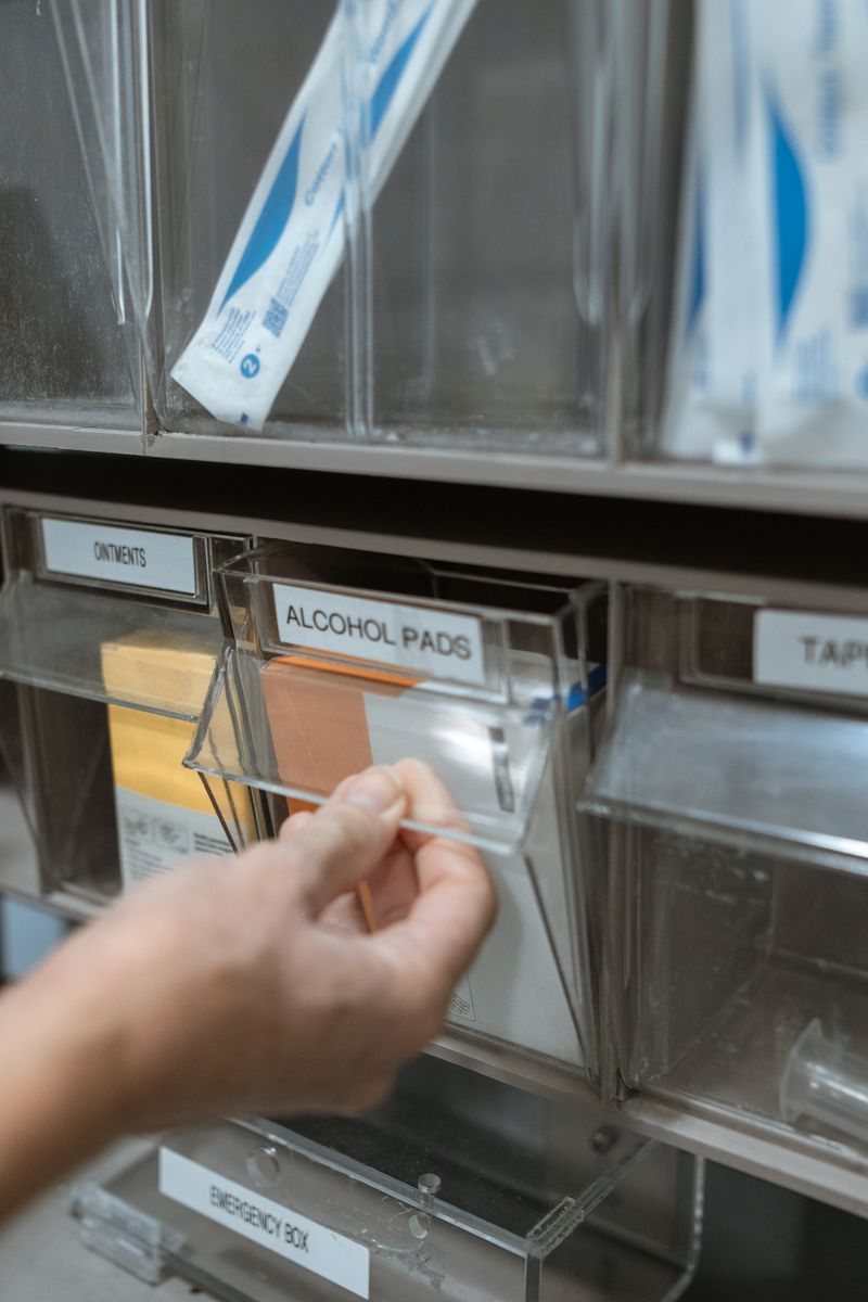 Hand taking alcohol pads from a wall-mounted supply dispenser