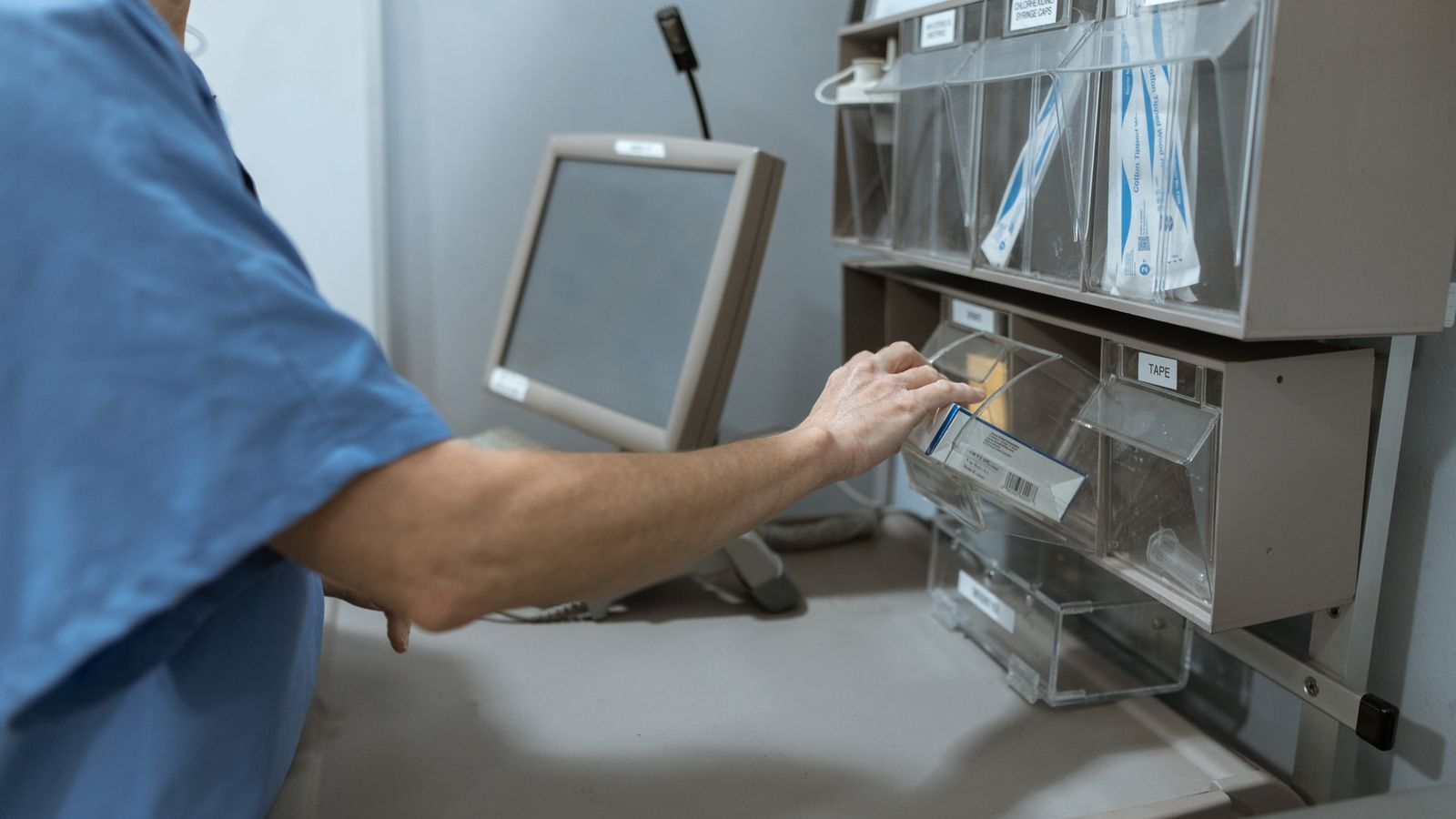 A healthcare worker organizing supplies on clinical shelving