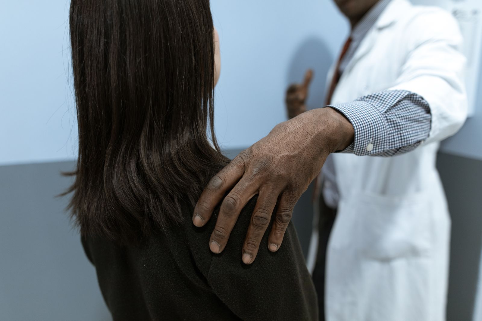Person gently holding the side of the neck and upper shoulder in bright natural light