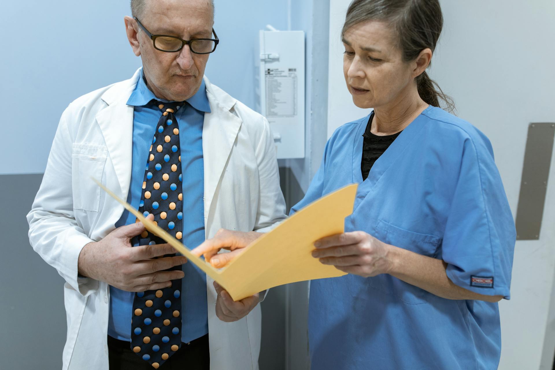 Doctor and nurse examining patient records in a clinical setting.