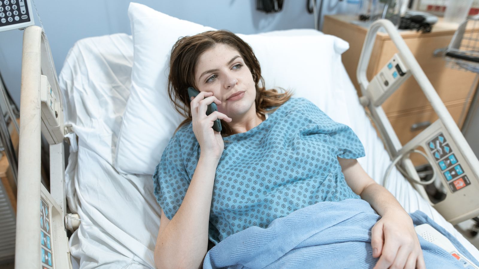 Woman in hospital bed talking on phone, representing healthcare and patient communication.