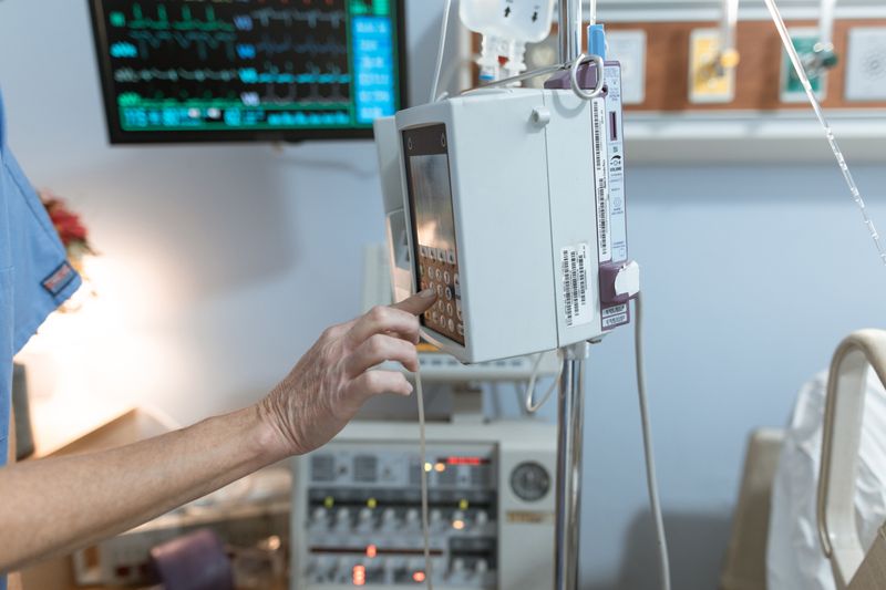 A healthcare worker operates a modern infusion pump in a hospital setting