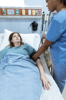 A nurse in scrubs monitors a patient's vitals in a hospital setting, providing healthcare care.