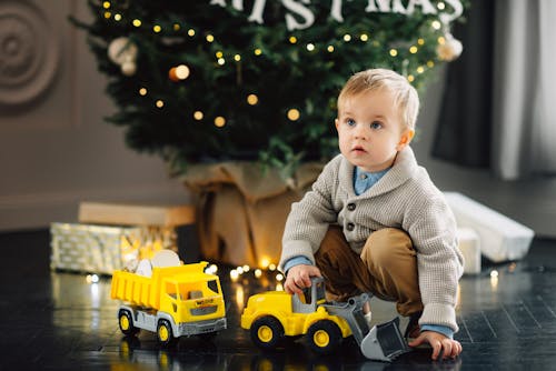 Child in Beige Knit Sweater playing a Toy Car