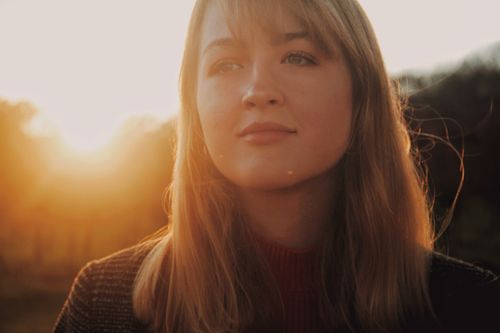 Free A serene portrait of a young woman in natural lighting during sunset, capturing a warm and peaceful moment. Stock Photo