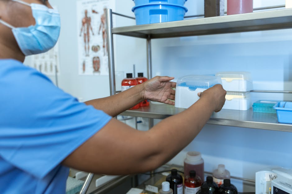 A medical professional organizes laboratory supplies on a shelf in a clinical setting.