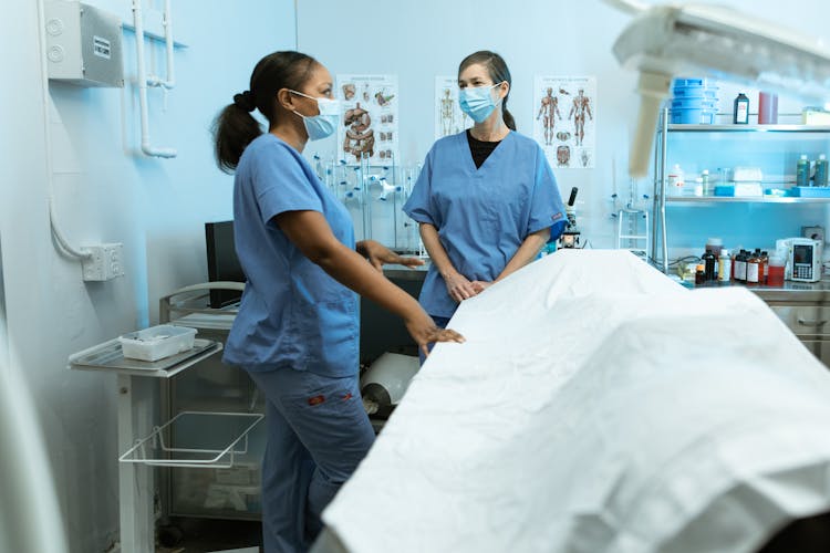 Two Female Nurses Talking With Facemasks On 