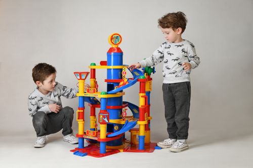Free Two boys engaging with a vibrant toy tower in a studio setting, showcasing playful childhood moments. Stock Photo