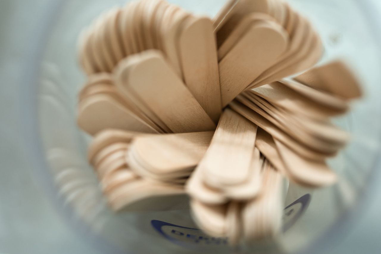 close up from above of wooden tongue depressors in a container showcas
