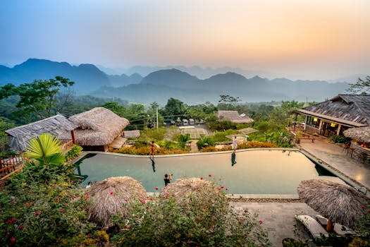 Tranquil tropical resort with pool and mountain views at dawn, perfect for relaxation.
