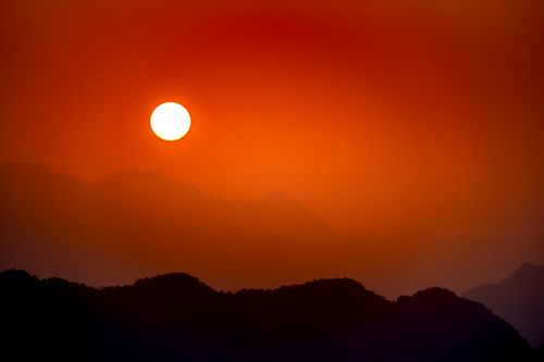 Free Bright sun shining on red cloudless sky over highland area with silhouettes of mountain ridge covered with mist at sundown time Stock Photo