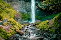 在宁静的户外，雄伟的瀑布从岩石悬崖上倾泻而下，四周环绕着充满活力的绿色植物