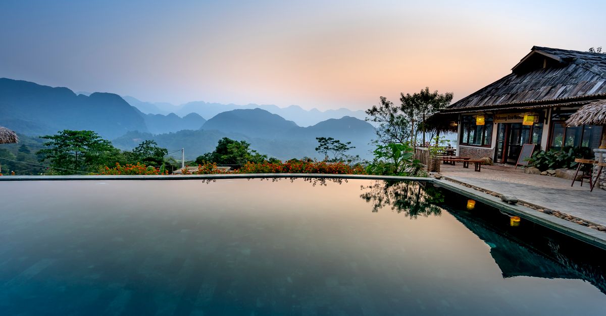 A small, locally-run hotel with a veranda and potted plants, overlooking a valley