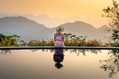 Anonymous lady sitting on poolside on sunset