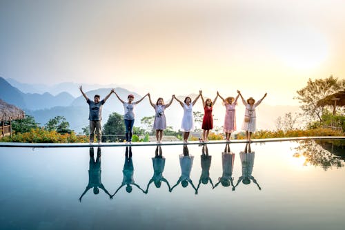 Free Group of happy people in colorful summer clothes raising hands and enjoying nature spending holidays together Stock Photo