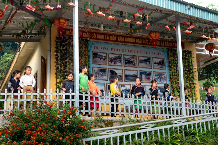 Asian Kids Near School Building On Terrace With Railing