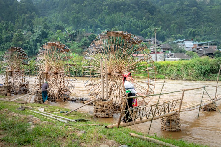 Female Standing Near Bamboo Water Mill In Countryside