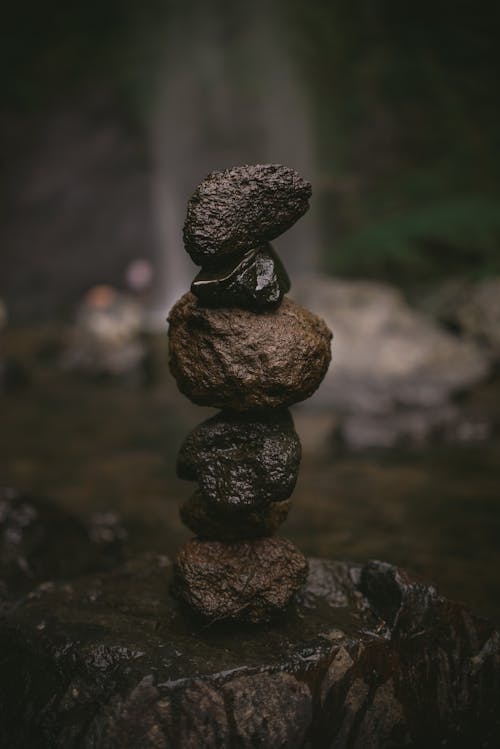 Small wet stones located on big rock placed on each other in nature in summer day