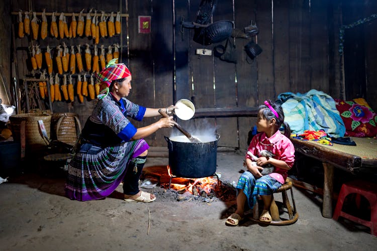 Woman Preparing Food On Bonfire White Daughter Sitting With Cat In Barn